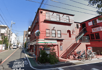 進み続けると、右手に1Fがセブンイレブンの赤い建物が見えます。ここがスタジオです。